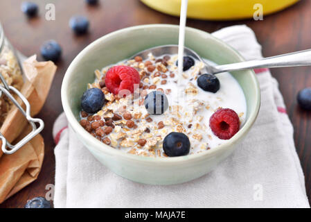 Getreide in einer Schüssel, Frühstück mit frischen Früchten und Müsli, das gesunde Essen. Frühstück Schüssel auf einem Holztisch, rustikalen Szene. Stockfoto