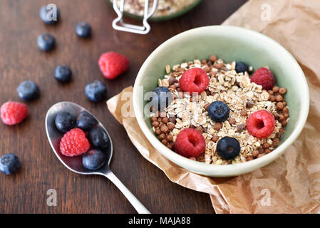 Getreide in einer Schüssel, Frühstück mit frischen Früchten und Müsli, das gesunde Essen. Frühstück Schüssel auf einem Holztisch, rustikalen Szene. Stockfoto