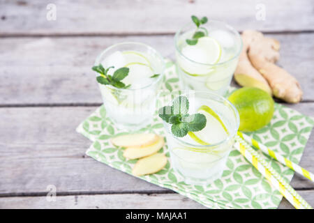 Hausgemachte Limonade mit Limette, Minze, Ingwer und Eis auf einem Holz- Hintergrund. Stockfoto