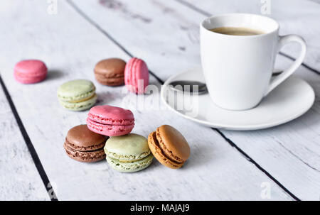 Leckere Makronen oder Macaron Kekse und Kaffee Tasse. Kaffeepause Szene mit bunte Macarons und weißer Tisch. Stockfoto