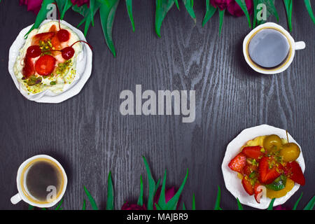 Schönen frischen Frühling Tulpe mit Tasse Kaffee und Obst Kuchen auf dunklem Hintergrund. Kaffee Zeit. Blume Geschenk. Pavlova pie Stockfoto