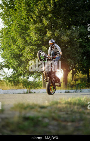 Ternopil, Ukraine - 28. August 2015: junge Biker ist beeindruckend mit seiner extremen Fähigkeiten auf Stadt Sommer Straßen. Grüne Bäume auf Hintergrund. durch das Tragen von schützender helm. Stockfoto