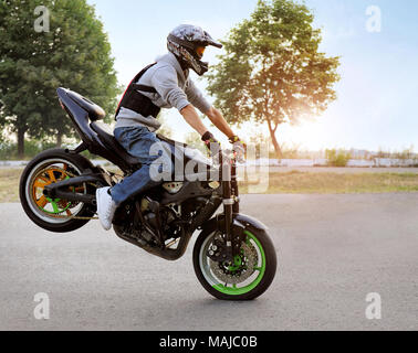 Ternopil, Ukraine - 28. August 2015: sich selbst zum Ausdruck zu bringen. Talentierte stunt Biker auf einem reiten Motorrad auf einem Rad. Sommer zitieren Straße gefüllt mit Licht der Sonne. Stockfoto