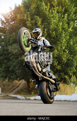 Ternopil, Ukraine - 28. August 2015: Porträt einer männlichen Biker zeigen extreme Talente auf einem Motorrad während der sonnigen Tag. Stuntman steht auf Hinterrad seines Sports Bike. Stockfoto