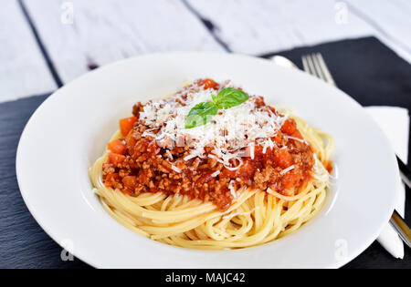 Leckere Pasta essen, Spaghetti Bolognese auf einem weißen Teller. Nudelgericht, traditionelle italienische Küche mit Parmesan Käse, Hackfleisch und Basil leaf. Stockfoto