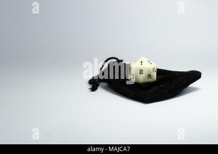 Weißer 20-seitige Würfel auf eine kleine schwarze Handtasche auf einem weißen Hintergrund. Würfel von Rollenspiel Stockfoto