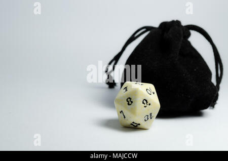 Weißer 20-seitige Würfel und eine kleine schwarze Handtasche auf einem weißen Hintergrund. Würfel von Rollenspiel und Kerker und Drachen. Stockfoto