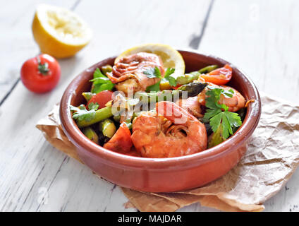 Frische tapas Platte mit Garnelen und grünem Spargel, Zitronenscheibe und Petersilie. Gourmet Teller auf eine weiße Holztisch. Stockfoto