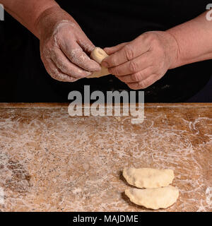 Die Hände eines alten Großmutter Schimmel vareniks auf einem dunklen Hintergrund 2018 Stockfoto