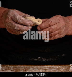 Die Hände eines alten Großmutter Schimmel vareniks auf einem dunklen Hintergrund 2018 Stockfoto