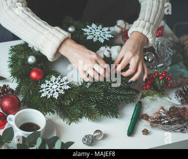 Weihnachten Konzept mit Evergreen Xmas Tree Zweig, rote Kugeln aus Glas und weibliche Hände Stockfoto