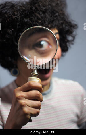 Frau halten und Schauen durch ein Vergrößerungsglas Stockfoto