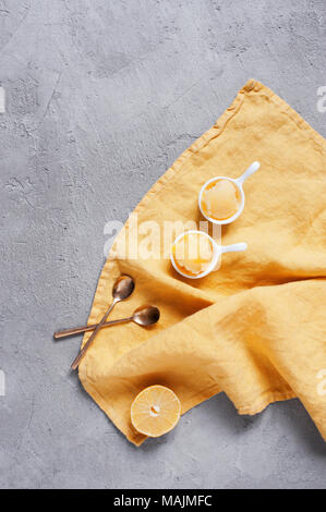 Zwei Portionen Zitronensorbet in die weiße Schüssel auf gelb serviette, strukturierte graue Tabelle. Ansicht von oben Stockfoto