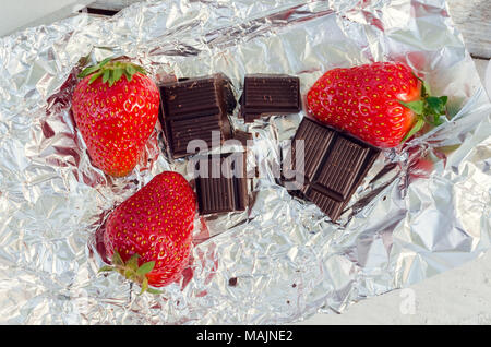 Erdbeeren mit Schokolade auf Folie wrapper Hintergrund. Gourmet Sommer Nachtisch. Ansicht von oben. Stockfoto