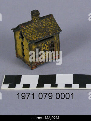 Gusseisen bank in Form eines Hauses mit einem Kamin in der Mitte des Daches und die vordere Tür mit Fenster flankierende auf jeder Seite. Zwei Fenster auf der Rückseite mit einer Münze Steckplatz oben. Titel: Haus Münze Bank (Small) (Gelb mit roter Zierleiste). ca. 1900. Stockfoto