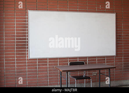 Ist Leer Lehrer Schreibtisch mit Whiteboard im Hintergrund. Kein Lehrer. Keine Studenten. Unterricht ohne Lehrer. Klassenzimmer ohne Studenten. Universität Klassenzimmer. Erwachsene Bildung. Stockfoto