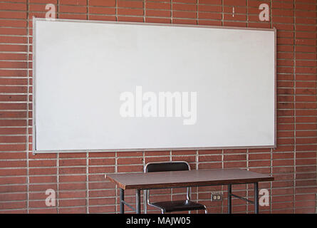 Ist Leer Lehrer Schreibtisch mit Whiteboard im Hintergrund. Kein Lehrer. Keine Studenten. Unterricht ohne Lehrer. Klassenzimmer ohne Studenten. Universität Klassenzimmer. Erwachsene Bildung. Stockfoto