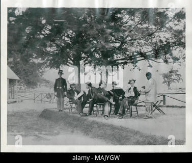 Gruppenfoto von fünf Männern, die Union Offiziere zu werden, eine Union eingetragenen Mann (wahrscheinlich ein eigenes), sowie eine Afrikanische amerikanische Diener. Die Männer sind unter zwei Bäumen und vor einem Zaun. Im Hintergrund ist die Ecke eines Gebäudes. Die ausgehuniform Mann hat eine Hardee Hut auf mit dem, was entweder gekreuzt Kanonen oder Säbel und einem Unternehmen schreiben. Titel: Nicht identifizierte Offiziere mit African American Attendant (Union). . Zwischen 1861 und 1865. Stockfoto