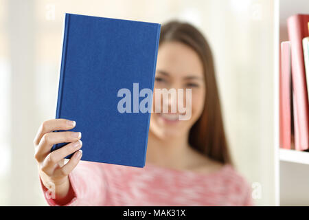 Glückliche Frau zeigt ein leeres Deckblatt eines Buches zu Hause Stockfoto