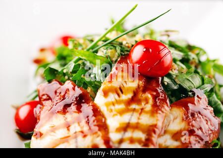 Salat serviert auf einem weißen Teller. Aal in einem Honig Sauce mit einem Salat aus einer Mischung mit Sesam bestreut, und ein paar frische Gemüse Gurke tomat Stockfoto