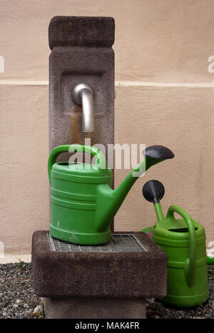 Zwei grüne Giesskannen an einer im Wasserhahn Stockfoto