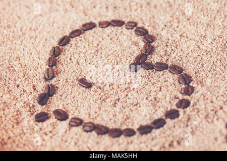 Herzform aus Kaffeebohnen auf auf Sand Stockfoto