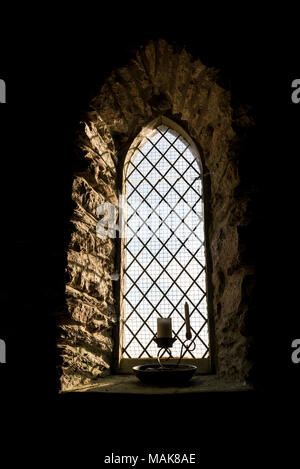 In der Nähe einer kleinen Kirche Fenster mit Kerzen auf dem Sims. Stockfoto