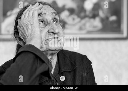 Schöne 80plus-jährigen Senior Frau Porträt. Schwarz-weiß Bild von älteren Menschen sorgen Frau auf einem Stuhl in einem Pflegeheim sitzen. Stockfoto