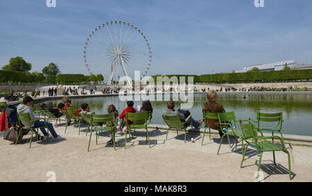 Die Leute sitzen auf grüne Stühle in den Tuilerien durch den Teich mit Blick auf den Großen Riesenrad, Ansicht von hinten. Paris, Frankreich Stockfoto