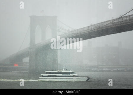 Ein privat eigene SeaStreak Fähre segeln nördlich auf dem East River verläuft unter der Brooklyn Bridge in einem Schneesturm Stockfoto