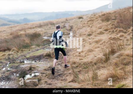 Ein Mann wird gesehen, die entlang einer schlammigen Pfad in den Hügeln auf einem kalten und nassen Nachmittag Stockfoto