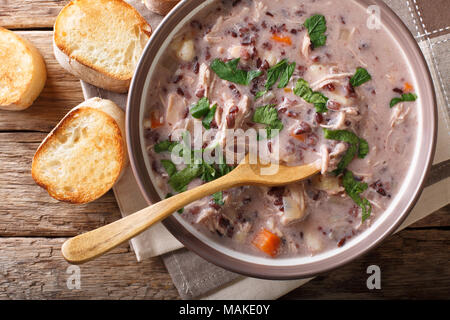 Suppe von wildem Reis mit Huhn und Gemüse close-up in eine Schüssel und Toast auf dem Tisch. horizontal oben Ansicht von oben Stockfoto