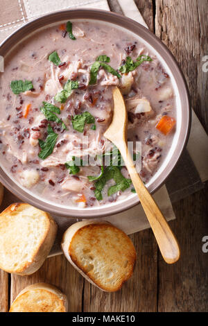 Suppe von wildem Reis mit Huhn und Gemüse close-up in eine Schüssel und Toast auf dem Tisch. Vertikal oben Ansicht von oben Stockfoto