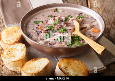 Natürliche Nahrung: wilder Reis Suppe mit Hähnchen und Gemüse close-up auf einem Teller und Toast auf einem Tisch. Horizontale Stockfoto