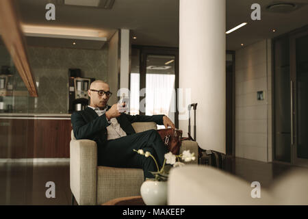 Geschäftsreisende in Airport Lounge warten und über Handy. Unternehmer warten auf Kampf an Airport Lounge. Stockfoto