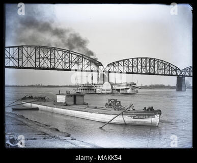 Horizontal, Schwarz und Weiß Foto, der steamboat Spread Eagle auf dem Mississippi Fluss in St. Louis, vorbei unter die Kaufleute Brücke. Der Spread Eagle ist in der Mitte des Bildes und eine grosse Rauchwolke driftet in Richtung der oberen linken Ecke des Bildes. Eine kleine Flussdampfer namens der Annie Spils ist am Deich im Vordergrund angedockt. Titel: Steamboat Spread Eagle auf dem Mississippi Fluss in St. Louis, vorbei unter die Kaufleute Brücke. . Zwischen 1900 und 1920. Stockfoto