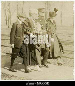 Vertikale, sepia Foto zeigt zwei Frauen, ein Mann in Uniform, und ein kleiner Junge auf einem Bürgersteig, möglicherweise in einem Park. Eine der Frauen erscheint Blumen zu halten. Titel: Zwei Frauen, ein Soldat, und ein Junge auf einem Bürgersteig, möglicherweise in einem Park. . Zwischen ca. 1914 und ca. 1918. Michel, Carl Stockfoto