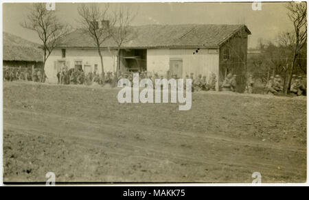 Horizontale, sepia Foto, uniformierte Soldaten neben einem Feldweg marschiert, vorbei an einem Haus. Eine bewaldete Fläche kann im Hintergrund des Bildes zu sehen. Titel: eine Gruppe von Soldaten marschieren hinter einem Haus neben einem Feldweg. . Zwischen ca. 1914 und ca. 1918. Michel, Carl Stockfoto