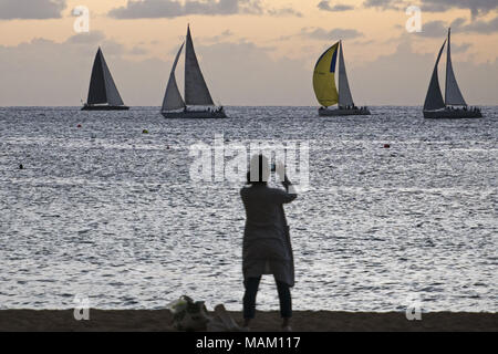Honolulu, Hawaii, USA. 15 Dez, 2017. Eine Frau nimmt ein Foto von Segelbooten aus Kaimana Beach, Honolulu, Hawaii. Der Strand ist auch als Sans Souci Strand bekannt und beliebt bei Einheimischen als auch Touristen. Credit: bayne Stanley/ZUMA Draht/Alamy leben Nachrichten Stockfoto