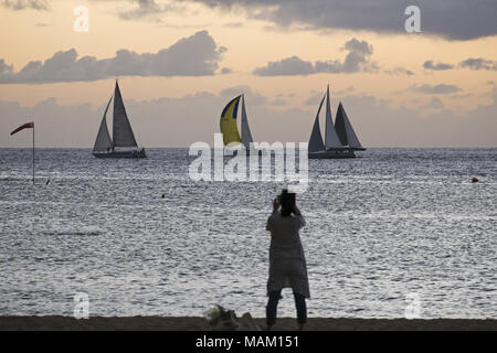 Honolulu, Hawaii, USA. 15 Dez, 2017. Eine Frau nimmt ein Foto von Segelbooten aus Kaimana Beach, Honolulu, Hawaii. Der Strand ist auch als Sans Souci Strand bekannt und beliebt bei Einheimischen als auch Touristen. Credit: bayne Stanley/ZUMA Draht/Alamy leben Nachrichten Stockfoto