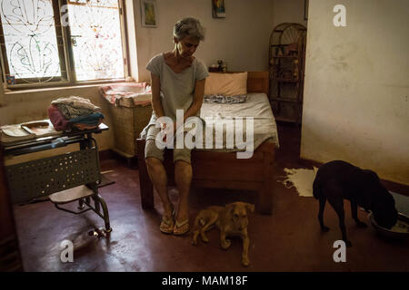 Kandy, Sri Lanka. 21 Feb, 2018. EVA RUPPEL sitzt auf ihrem Bett, in ihrem ländlichen Anwesen in der Nähe von Kandy, Sri Lanka, während Sie zwei Street Dogs Sie gerettet, am Mittwoch, 21. Februar 2018. Ruppel nicht Käfig die ungefähre 170 geretteten Hunde, das Ihr Haus teilen, die es Ihnen ermöglichen, Bewegungsfreiheit und interagieren in Kleinpackungen in mehrere Stifte in ihrer Eigenschaft als auch innerhalb Ihres Hauses. Ruppel erstellt Tikiri Vertrauen, mit der finanziellen Unterstützung ihres Vaters, zu retten und rehome Sri Lanka's Street Dogs. Es ist unmöglich, Sri Lanka, ohne zu sehen, Street Dogs in fast jedem öffentlichen zu besuchen s Stockfoto