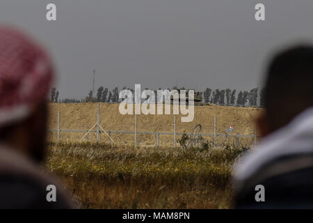 Palästinensische Demonstranten stare an einem israelischen Panzer bei Zusammenstößen an der Grenze zwischen Israel und Gaza, östlich von Khan Yunis, im südlichen Gazastreifen, 03. April 2018. Foto: Mohammed Talatene/dpa Stockfoto