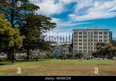 San Francisco, CA: Die Painted Ladies in der Steiner Straße mit Blick auf Alamo Square und die moderne Skyline der Stadt. Stockfoto