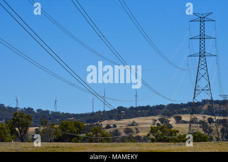 Strommasten mit Windparks Turbinen im Hintergrund in Inverell in New South Wales, Australien Stockfoto