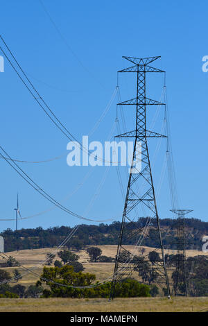 Strommasten mit Windparks Turbinen im Hintergrund in Inverell in New South Wales, Australien Stockfoto