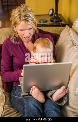30 ish Mutter und ihrem Baby Boy Spielen zusammen mit einem Laptop. Stockfoto