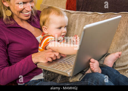 30 ish Mutter und ihrem Baby Boy Spielen zusammen mit einem Laptop. Stockfoto