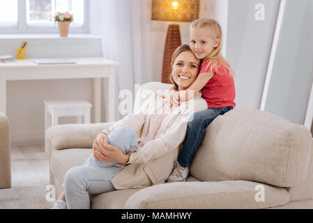 Niedlich smiley Mädchen ihre Mutter umarmt Stockfoto