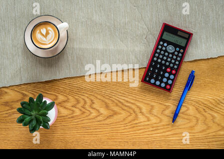 Buchhalter Arbeitsbereich als Flach von oben mit Ziffern in den Taschenrechner, Anlagen und Kaffee mit Holz- Hintergrund Stockfoto