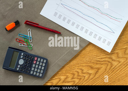 Buchhalter Arbeitsbereich als Flach von oben mit Unterlagen und Dokumente mit Zahlen in Diagrammen, Büroklammern und Rechner mit Holz- Hintergrund Stockfoto